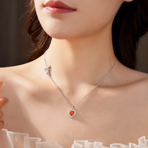 Detail of silver heart necklace with red stone pendant and small bear charm decoration