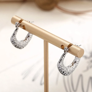 Detailed view of silver U-shaped earrings with unique hammered texture on display stand