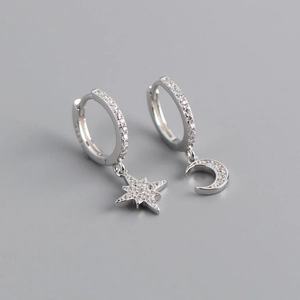Macro shot of asymmetric s925 silver star and moon earrings with cubic zirconia stones