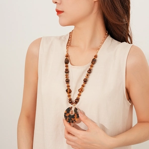 Gros plan du collier avec pendentif léopard, perles marron et chaîne dorée élégante