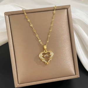 Gold winged heart necklace with zircon stone in a jewelry box on white silk fabric