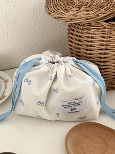 Detail of cream tissue storage bag featuring blue bow prints and woven brand label