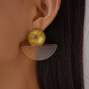 Detail of model wearing geometric resin drop earrings in gold and translucent brown