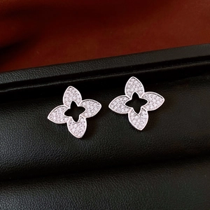 Detail view of silver hollow flower stud earrings with shimmering zircon stones