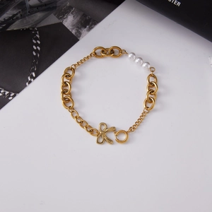 Detailed macro of gold chain bracelet featuring three pearls and a bow clasp design