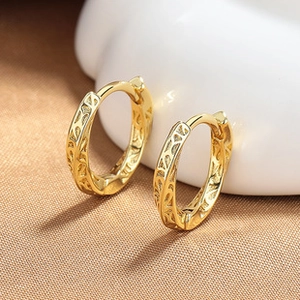 Macro detail of vintage gold hoop earrings with intricate hollow-out floral patterns