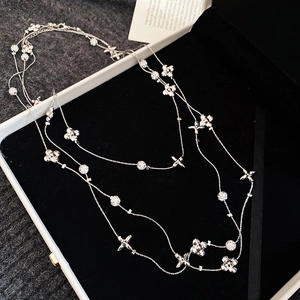 Macro view of multi-layer silver clover necklace with textured beads on black velvet