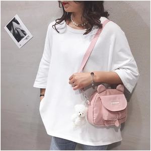 Close-up of pink canvas shoulder bag featuring a cute white plush bear charm and ears