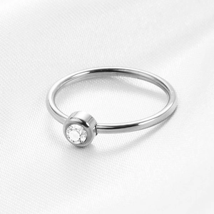 Macro shot of silver stainless steel ring with a round zircon stone on white silk