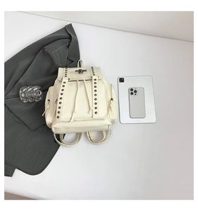 Flat lay of white studded backpack with drawstring and silver rivets on a white background