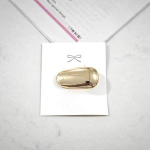 Macro detail of golden alloy hair clip with polished finish on a white card display