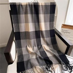 Close-up of black and beige plaid scarf with soft tassels on a chair with soft lighting