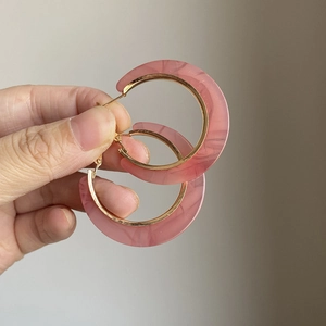 Hellrosa Acetat-Creolen mit goldenem Metallrand handgehalten zur Größenveranschaulichung