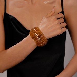 Détail d'un bracelet vintage en acrylique ambré avec des motifs ondulés sur le poignet