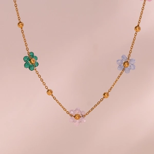 Detail view of gold bead chain featuring emerald, blue, and pink crystal flower charms