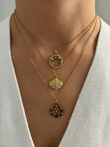 Close-up of layered gold necklaces with shell and starburst pendants on model