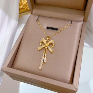 Detail of gold bow necklace with lustrous pearl and sparkling zircon in a gift box