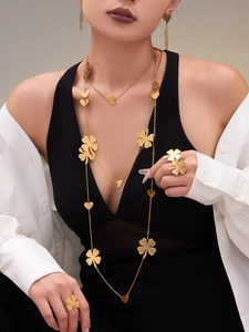 Golden four-leaf clover and heart jewelry set worn by a model in professional studio light