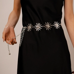 Detail view of vintage silver sun mask metal waist chain on a black dress