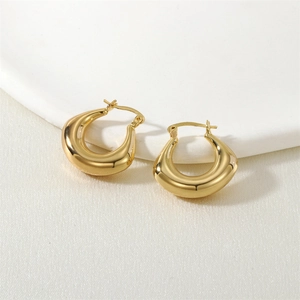Macro detail of glossy golden teardrop earring with polished mirror finish on a stone base
