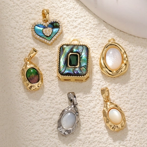Detail of luxury abalone and mother of pearl pendants on a textured sandy surface
