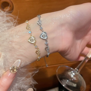 Close-up of gold and silver hollow heart bracelets with mother of pearl and zircon details