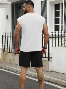 Rear view of man in white sleeveless shirt and black shorts on a modern street