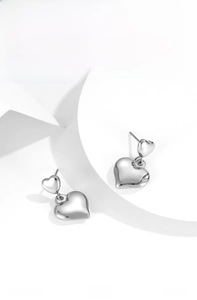 Detailed close-up of shiny heart-shaped silver earrings with polished mirror finish