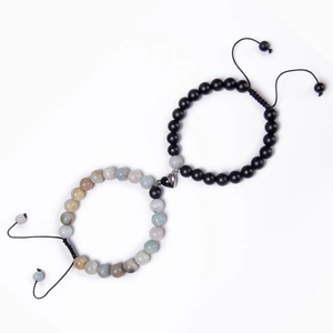 Detail of heart-shaped magnetic clasp connecting matte black and natural stone bead bracelets