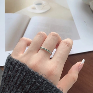 Detail shot of a minimalist S925 sterling silver ring with emerald green cubic zirconia