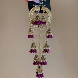 Detail of vintage gold leaf tassel earrings with purple beads and intricate metalwork
