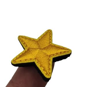Yellow star embroidered patch with black reinforced border held by hand against white back