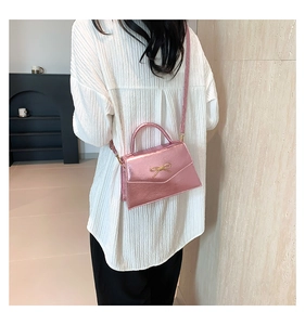 Détails du mini sac bandoulière rose métallisé avec nœud doré porté par un mannequin
