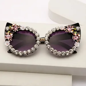 Black cat-eye sunglasses with rhinestone edges and pink stones on a stone stand