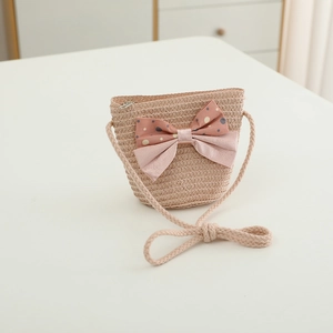 Detailed macro view of a mini straw crossbody bag featuring a pink polka dot bow decoration