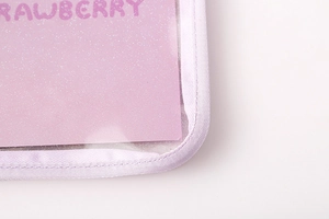 Macro detail of transparent PVC binder pocket with purple fabric edging and pink glitter card