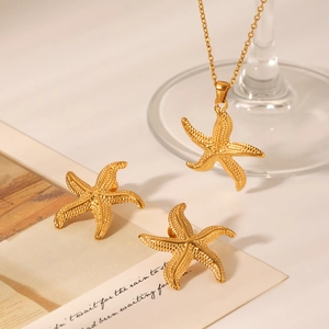 Gros plan détaillé du parure collier et boucles d'oreilles étoile de mer dorée