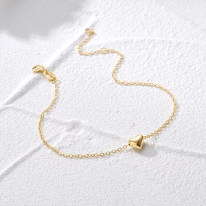 Detailed close-up of a golden minimalist chain bracelet with a 3D heart-shaped pendant
