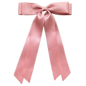 Detail of pink satin double-layered bow hair clip with long ribbons on white background
