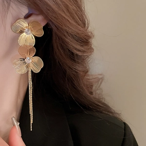 Gros plan de boucles d'oreilles fleurs dorées avec pompons longs et cœurs brillants