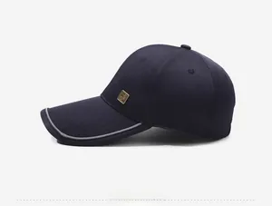 Detail of navy baseball cap with gold metal logo and reflective brim trim on twill fabric