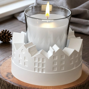 Detail of a ceramic house relief candle holder set on a rustic wooden base with pinecone