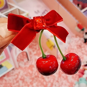 Gros plan sur un nœud de cheveux en velours rouge avec breloques cerise et paillettes