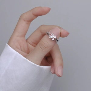 Silver flower ring with four-leaf clover zircon petals on a woven braided band