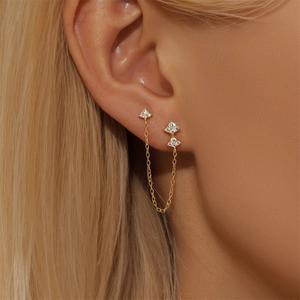 Detail of gold double piercing ear chain with cz flower petals on a female model