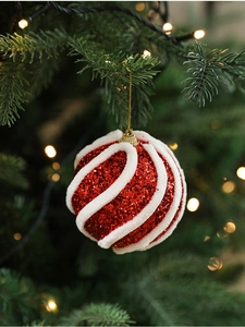 Detail einer roten Glitzer-Weihnachtskugel mit weißer Spirale am Weihnachtsbaum