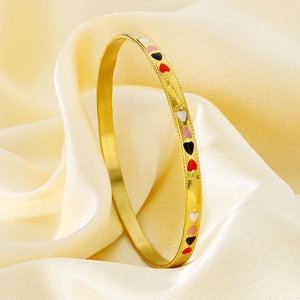 Detail of 18K gold plated stainless steel bangle featuring colorful enamel heart patterns