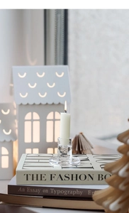 Clear crystal glass candle holder on fashion books with a lit white taper candle