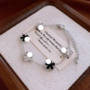 Macro detail of silver-tone clover bracelet with black and textured floral charms