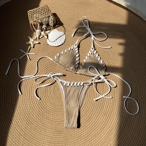 Two-piece khaki ribbed bikini set with white rope ties and eyelets on woven mat